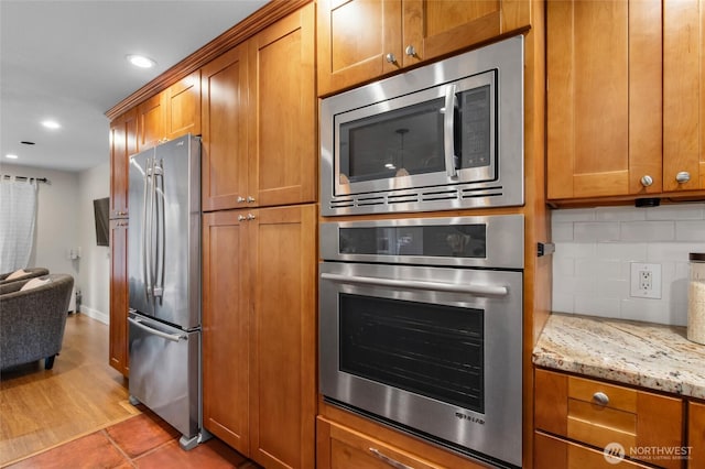 315 10th Ave S Unit 101, Kirkland, WA 98033 - kitchen with stainless steel appliances, brown cabinets, backsplash, recessed lighting, and light stone counters