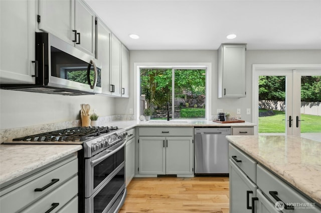 32910 NE 40th Pl, Carnation, WA 98014 - kitchen featuring stainless steel appliances, french doors, light wood-type flooring, light stone counters, and a sink