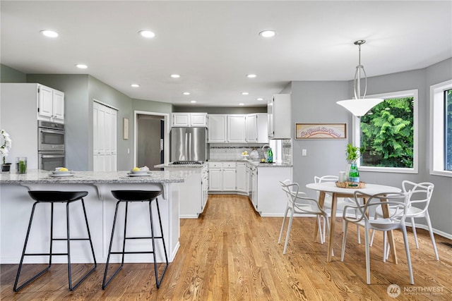 2110 216th Pl NE, Sammamish, WA 98074 - kitchen with appliances with stainless steel finishes, a peninsula, a kitchen breakfast bar, white cabinets, and recessed lighting
