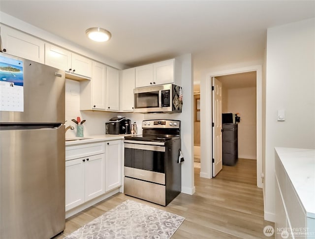3834 175th Ave NE Unit G16, Redmond, WA 98052 - kitchen featuring stainless steel appliances, light wood finished floors, white cabinetry, a sink, and light countertops