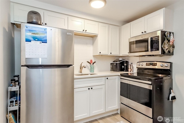 3834 175th Ave NE Unit G16, Redmond, WA 98052 - kitchen with stainless steel appliances, a sink, white cabinetry, light countertops, and light wood-style flooring