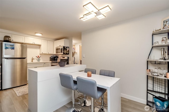 3834 175th Ave NE Unit G16, Redmond, WA 98052 - kitchen featuring stainless steel appliances, light countertops, white cabinets, light wood-style flooring, and a kitchen breakfast bar