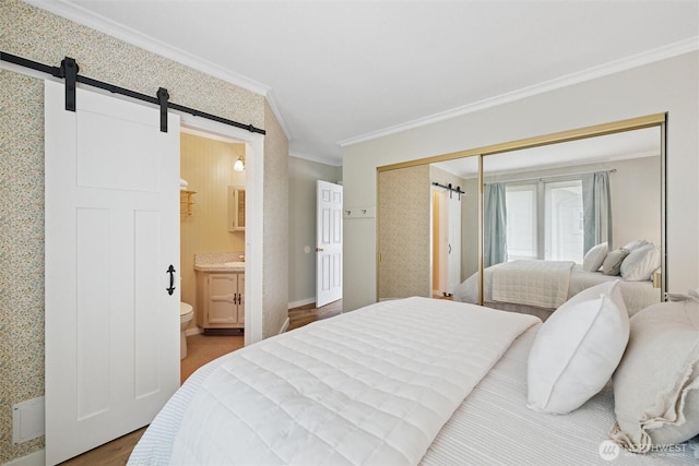 2828 Sunset Dr, Bellingham, WA 98225 - bedroom featuring ornamental molding, a barn door, ensuite bathroom, a closet, and wood finished floors
