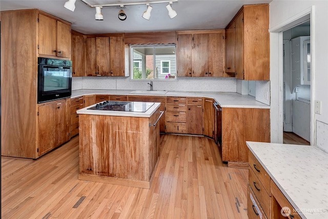 4604SW Lander St, Seattle, WA 98116 - kitchen with black appliances, a sink, brown cabinetry, light wood-style flooring, and light countertops