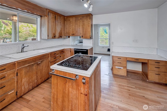 4604SW Lander St, Seattle, WA 98116 - kitchen featuring a sink, light wood-style flooring, black appliances, a center island, and brown cabinets