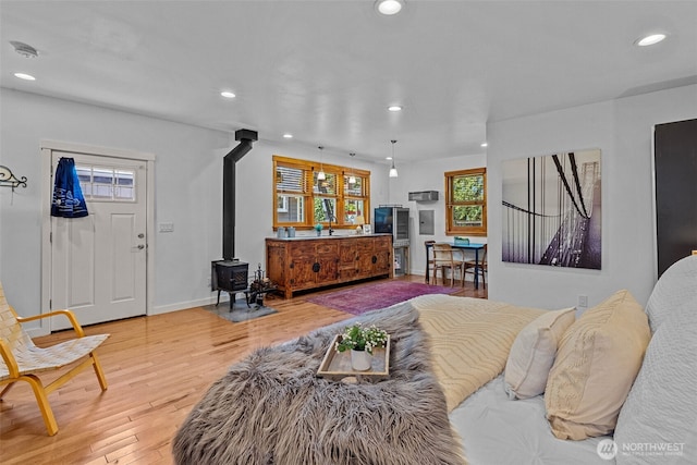 7510 Fauntleroy Way SW, Seattle, WA 98136 - bedroom featuring a wood stove, recessed lighting, multiple windows, light wood-style flooring, and baseboards