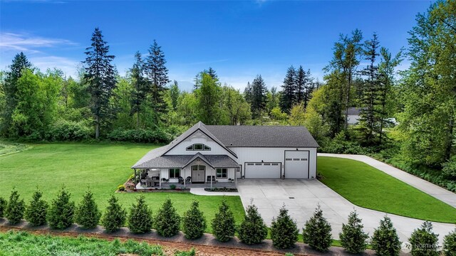 2495 River Rock Dr, Everson, WA 98247 - view of front facade featuring a front lawn, concrete driveway, a porch, a garage, and a wooded view
