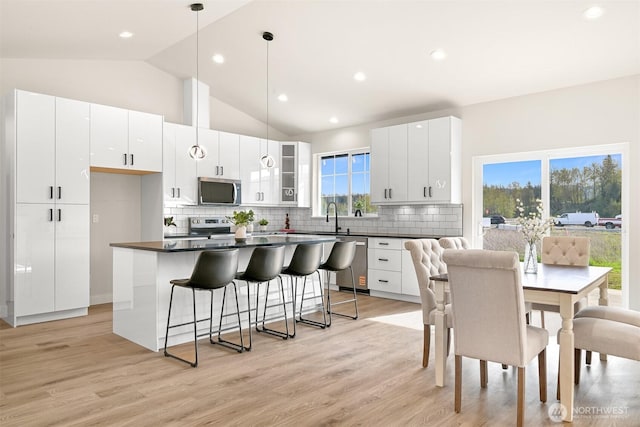 710 E 4th St, Nooksack, WA 98276 - kitchen featuring stainless steel appliances, a kitchen bar, dark countertops, vaulted ceiling, and a sink