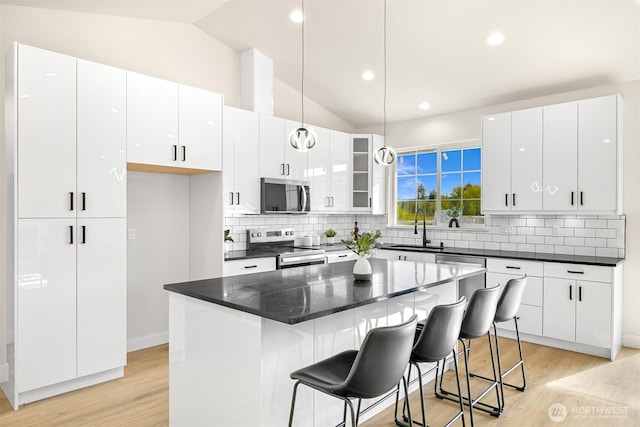 710 E 4th St, Nooksack, WA 98276 - kitchen featuring appliances with stainless steel finishes, a sink, vaulted ceiling, white cabinets, and a kitchen breakfast bar