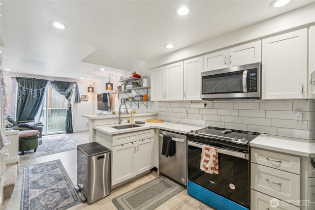 903 N 130th St Unit 113, Seattle, WA 98133 - kitchen featuring appliances with stainless steel finishes, a sink, white cabinetry, a peninsula, and recessed lighting