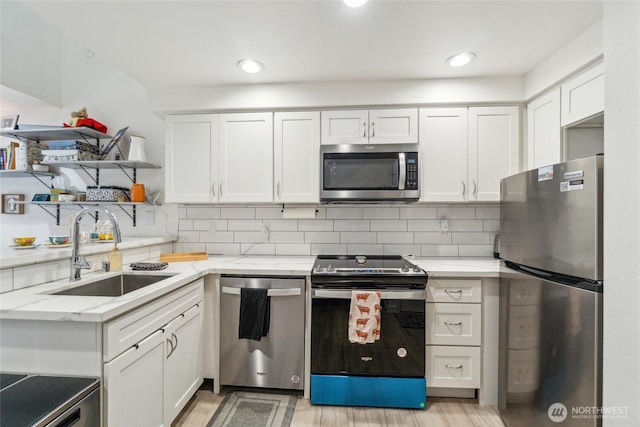 903 N 130th St Unit 113, Seattle, WA 98133 - kitchen with appliances with stainless steel finishes, a sink, open shelves, light wood-type flooring, and white cabinetry