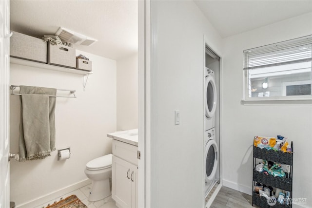903 N 130th St Unit 113, Seattle, WA 98133 - bathroom featuring stacked washer / dryer, baseboards, vanity, and toilet