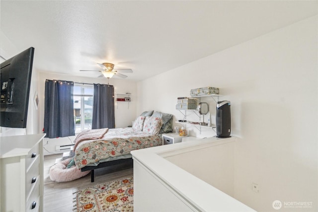 903 N 130th St Unit 113, Seattle, WA 98133 - bedroom with baseboard heating, light wood-type flooring, and ceiling fan