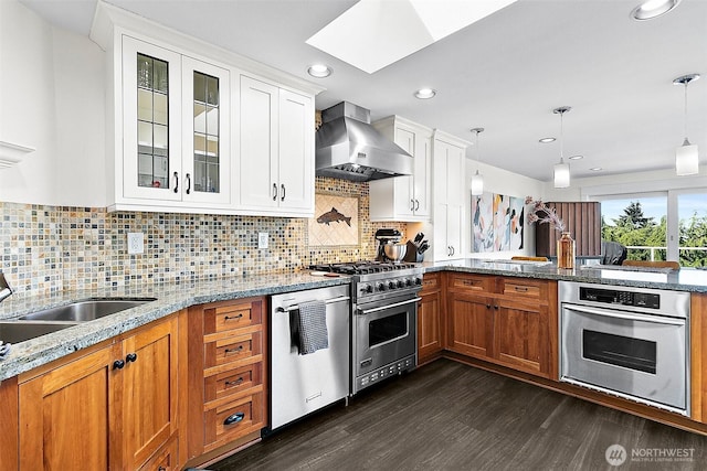 5758 Overlook Ave NE, Tacoma, WA 98422 - kitchen with stainless steel appliances, wall chimney range hood, a peninsula, dark wood-style floors, and glass insert cabinets