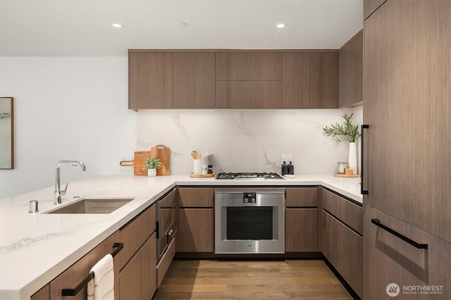 188 Bellevue Way NE Unit 307, Bellevue, WA 98004 - kitchen with oven, a sink, light wood-style floors, a peninsula, and modern cabinets
