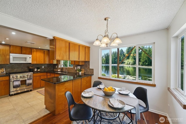 35029 37th Ave S, Auburn, WA 98001 - kitchen featuring white microwave, high end stove, brown cabinets, a peninsula, and a chandelier