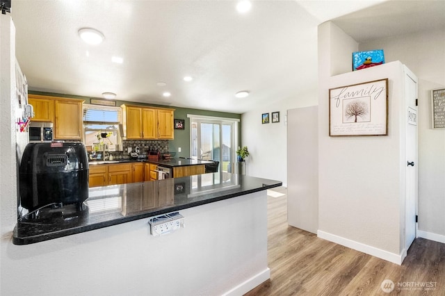 3327 Firouzi Dr NE, Moses Lake, WA 98837 - kitchen with a peninsula, stainless steel microwave, light wood-style floors, decorative backsplash, and a sink