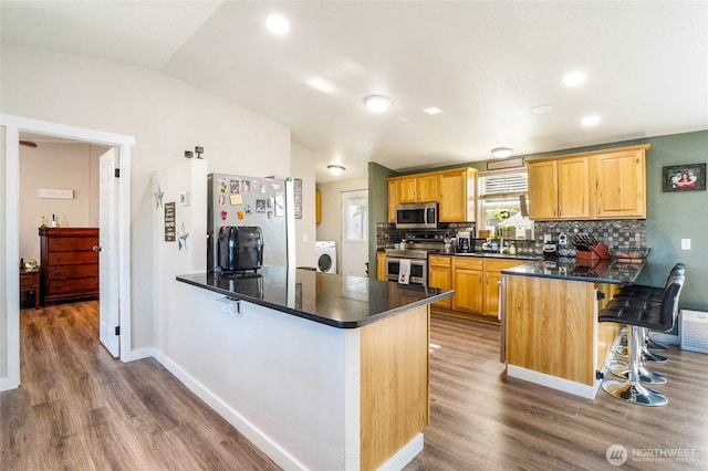 3327 Firouzi Dr NE, Moses Lake, WA 98837 - kitchen with appliances with stainless steel finishes, a peninsula, washer / dryer, a kitchen breakfast bar, and vaulted ceiling