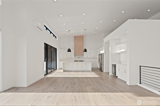 20519 Benson Ridge Ln, Mount Vernon, WA 98274 - unfurnished living room featuring a high ceiling, light wood-style flooring, wine cooler, recessed lighting, and baseboards