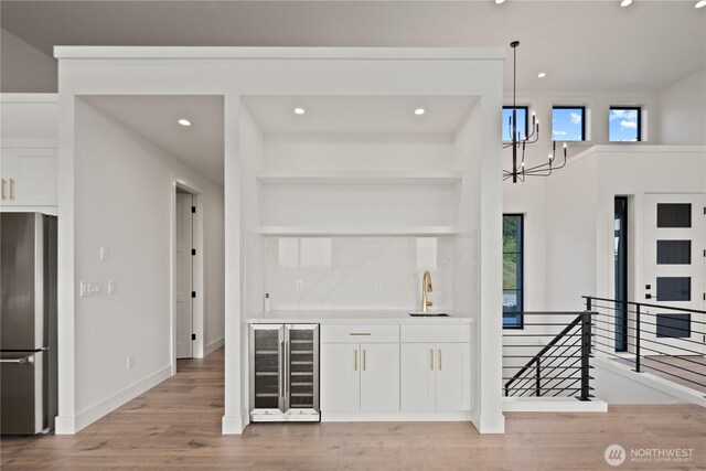 20519 Benson Ridge Ln, Mount Vernon, WA 98274 - indoor wet bar with freestanding refrigerator, beverage cooler, light wood-type flooring, a chandelier, and recessed lighting