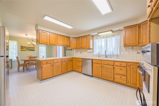 1160 Cays Rd, Sequim, WA 98382 - kitchen with appliances with stainless steel finishes, a sink, a peninsula, and decorative backsplash