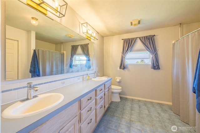 1160 Cays Rd, Sequim, WA 98382 - bathroom with double vanity, toilet, baseboards, backsplash, and a shower with curtain