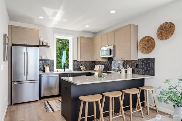 2817 Franklin Ave E Unit A, Seattle, WA 98102 - kitchen with appliances with stainless steel finishes, a sink, a peninsula, decorative backsplash, and recessed lighting