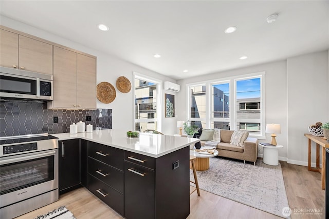 2817 Franklin Ave E Unit A, Seattle, WA 98102 - kitchen with appliances with stainless steel finishes, a peninsula, a kitchen breakfast bar, decorative backsplash, and light countertops