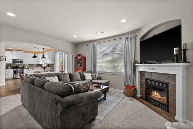 4415 Goldcrest Dr NW, Olympia, WA 98502 - living room featuring arched walkways, a tile fireplace, baseboards, recessed lighting, and wood finished floors