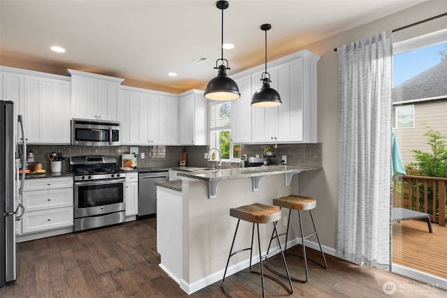 4415 Goldcrest Dr NW, Olympia, WA 98502 - kitchen with stainless steel appliances, dark wood finished floors, a peninsula, white cabinetry, and recessed lighting