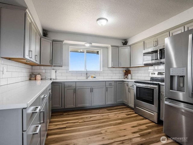 13576 NE Rd 10, Moses Lake, WA 98837 - kitchen featuring stainless steel appliances, gray cabinets, a sink, a textured ceiling, and wood finished floors