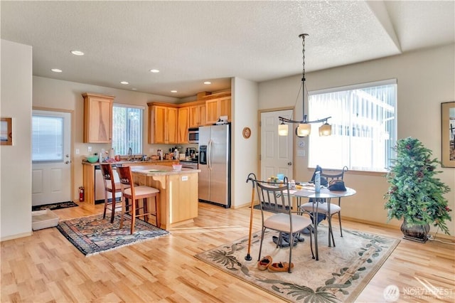 152 N Oar Loop NW, Ocean Shores, WA 98569 - kitchen featuring appliances with stainless steel finishes, a center island, light countertops, light wood-type flooring, and a textured ceiling