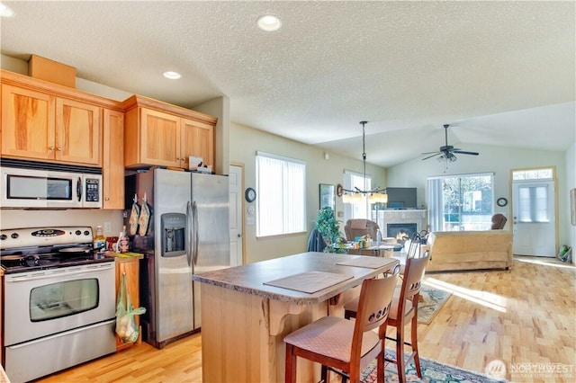 152 N Oar Loop NW, Ocean Shores, WA 98569 - kitchen with stainless steel appliances, a glass covered fireplace, light wood finished floors, ceiling fan, and a textured ceiling