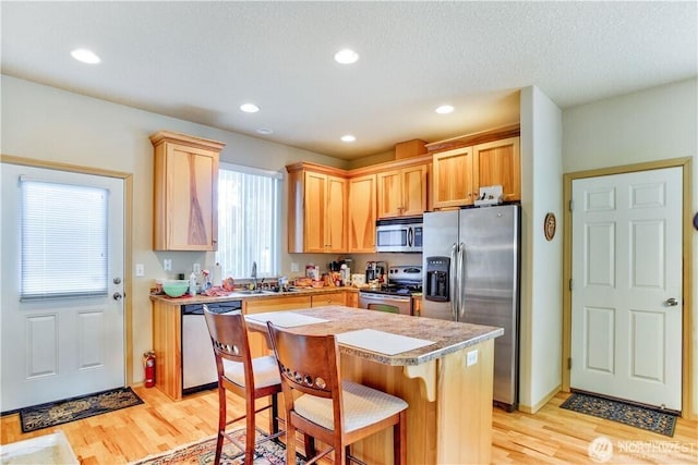 152 N Oar Loop NW, Ocean Shores, WA 98569 - kitchen featuring stainless steel appliances, light wood finished floors, light brown cabinets, a sink, and a kitchen island