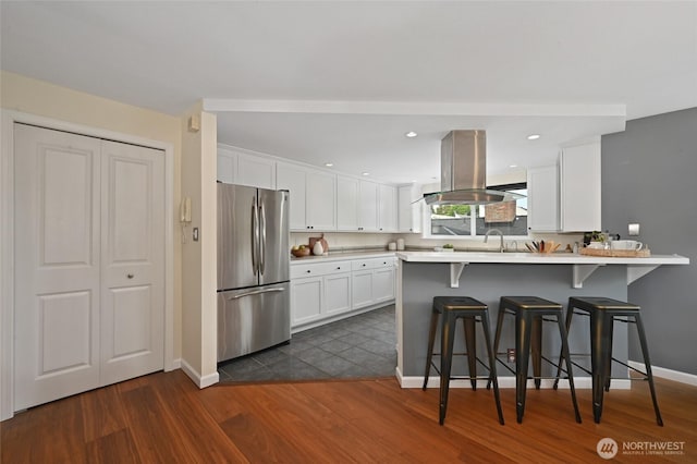 3633 22nd Ave W Unit C, Seattle, WA 98199 - kitchen with freestanding refrigerator, island range hood, dark wood-type flooring, a kitchen bar, and white cabinetry