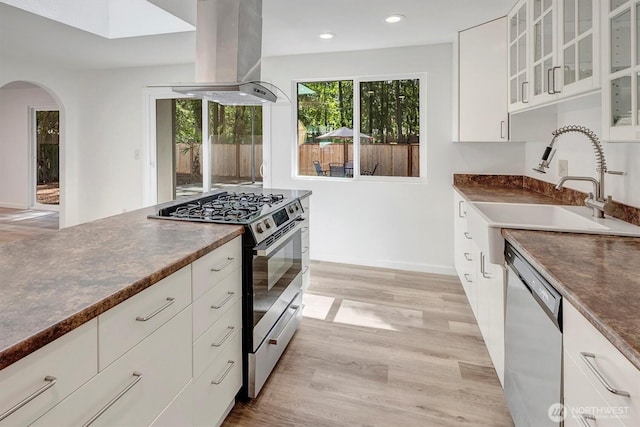 19055 SE 269th St, Covington, WA 98042 - kitchen featuring stainless steel appliances, island range hood, arched walkways, dark countertops, and a sink