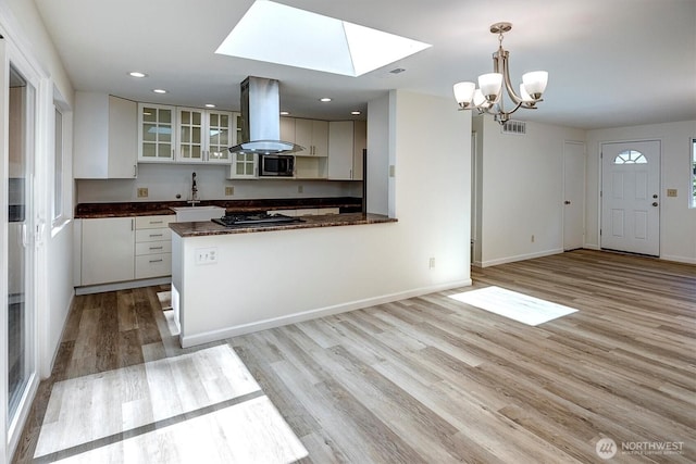 19055 SE 269th St, Covington, WA 98042 - kitchen featuring island exhaust hood, stainless steel microwave, dark countertops, a skylight, and a chandelier