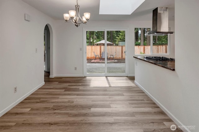 19055 SE 269th St, Covington, WA 98042 - unfurnished dining area with arched walkways, a chandelier, light wood-style flooring, baseboards, and a skylight