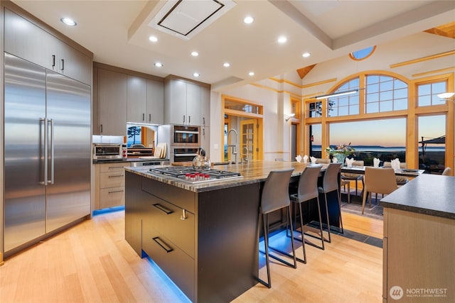 33020 84th Ave NW, Stanwood, WA 98292 - kitchen with appliances with stainless steel finishes, a large island with sink, light wood-style floors, a breakfast bar area, and recessed lighting