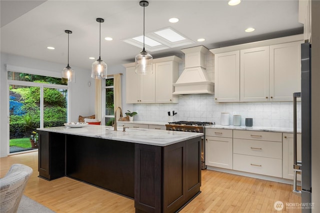 8122 104th Street Ct SW, Lakewood, WA 98498 - kitchen with custom range hood, high end stainless steel range, light wood finished floors, backsplash, and recessed lighting