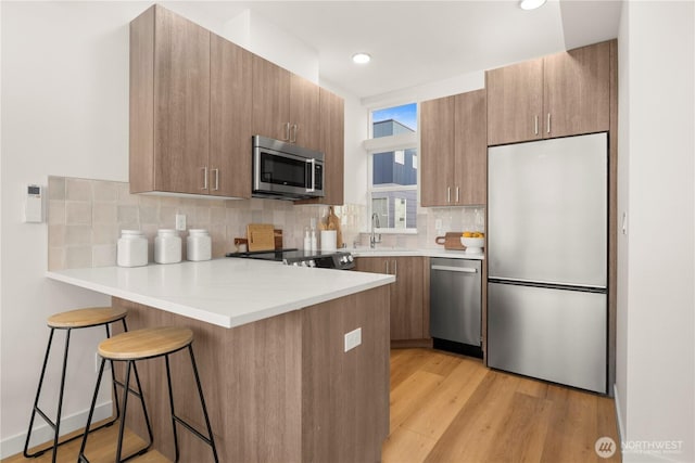 1206C NW 83rd St, Seattle, WA 98117 - kitchen featuring appliances with stainless steel finishes, a peninsula, a sink, a breakfast bar area, and decorative backsplash