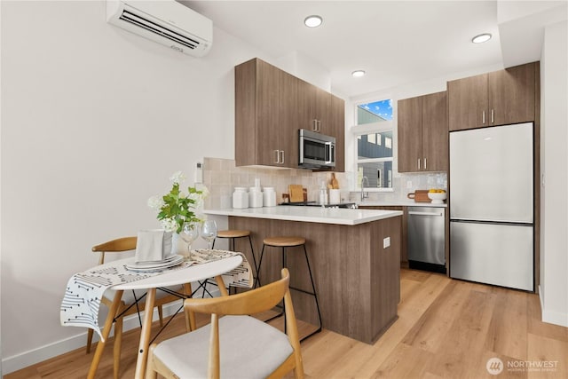 1206C NW 83rd St, Seattle, WA 98117 - kitchen with appliances with stainless steel finishes, an AC wall unit, backsplash, a peninsula, and light countertops