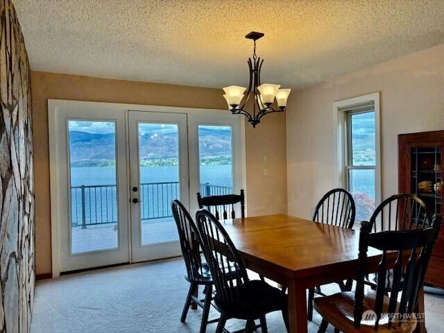 56 Westlake Rd, Oroville, WA 98844 - dining area with light colored carpet, a textured ceiling, a chandelier, and french doors