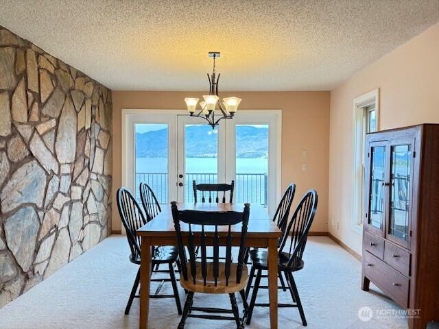 56 Westlake Rd, Oroville, WA 98844 - dining area featuring light carpet, a chandelier, a textured ceiling, and baseboards