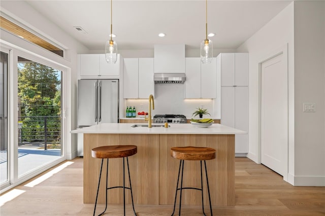 6730 21st Ave SW, Seattle, WA 98106 - kitchen with exhaust hood, light countertops, a kitchen island with sink, white cabinetry, and recessed lighting