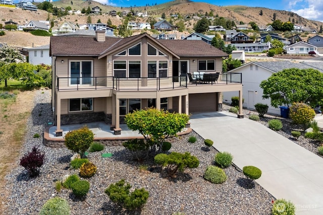 205 Butte Rd, Chelan, WA 98816 - view of front of house with stone siding, a residential view, a mountain view, a balcony, and concrete driveway