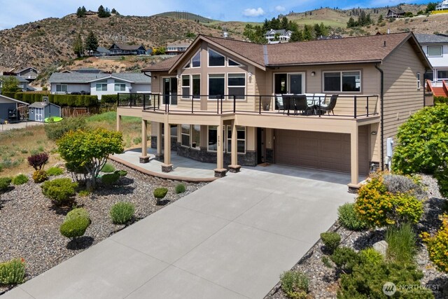 205 Butte Rd, Chelan, WA 98816 - rear view of house featuring a mountain view, an attached garage, driveway, a balcony, and a residential view