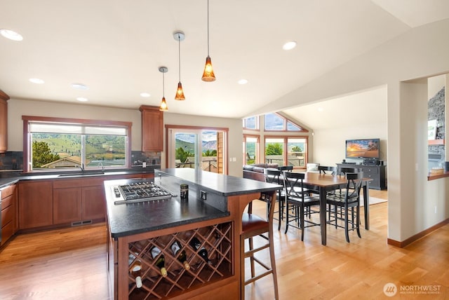 205 Butte Rd, Chelan, WA 98816 - kitchen featuring dark countertops, decorative backsplash, light wood-type flooring, a kitchen breakfast bar, and lofted ceiling