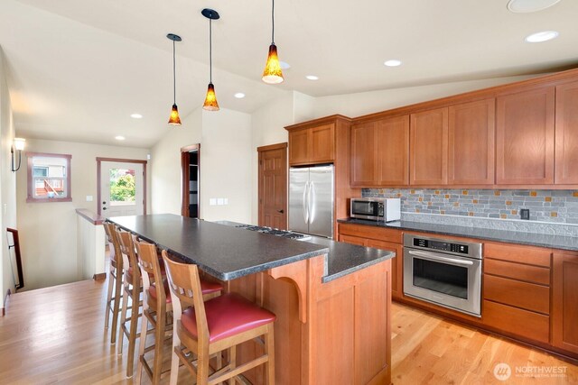 205 Butte Rd, Chelan, WA 98816 - kitchen with stainless steel appliances, vaulted ceiling, light wood-type flooring, brown cabinetry, and a kitchen island
