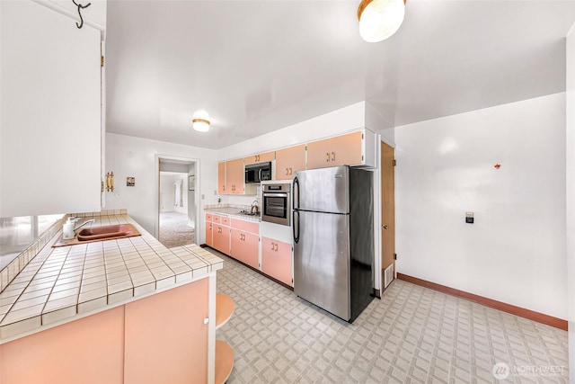 420 E Connecticut St, Bellingham, WA 98225 - kitchen with stainless steel appliances, a sink, tile counters, light carpet, and baseboards
